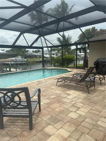 Swimming pool with a patio area, glass enclosure, grilling area, and a boat dock
