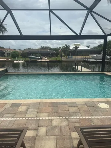 Swimming pool with glass enclosure, a water view, and a dock