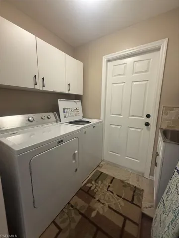 Washroom featuring independent washer and dryer and cabinet space