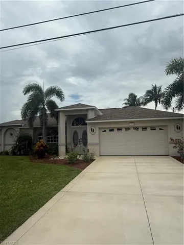 Ranch-style house with concrete driveway, stucco siding, a garage, and a front yard