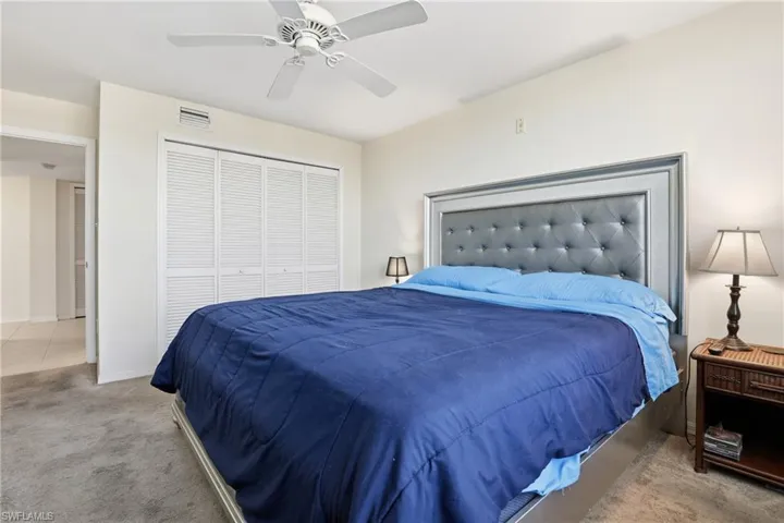 Bedroom with light carpet, ceiling fan, and a closet