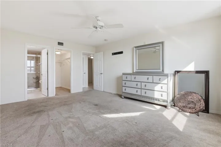 Unfurnished bedroom with a walk in closet, light carpet, ceiling fan, and ensuite bathroom