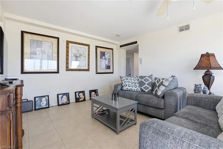 Living room with light tile patterned floors and a ceiling fan