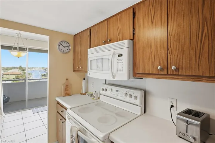 Kitchen with white appliances, brown cabinetry, light countertops, and light tile patterned flooring