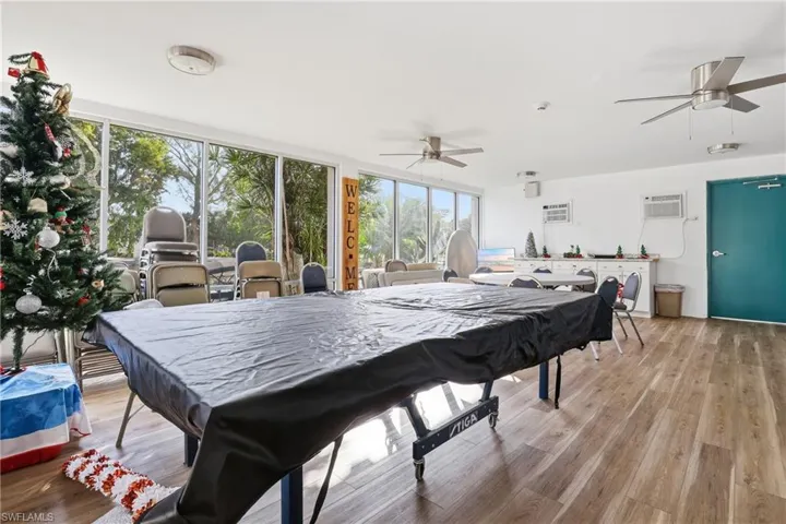Rec room with ceiling fan, wood finished floors, floor to ceiling windows, and a wall mounted AC