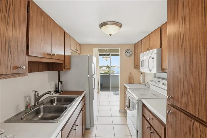 Kitchen with white appliances, light countertops, light tile patterned flooring, and brown cabinets