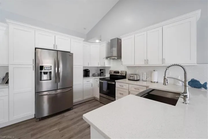 Kitchen featuring appliances with stainless steel finishes, stainless and glass wall chimney range hood, sink, decorative backsplash