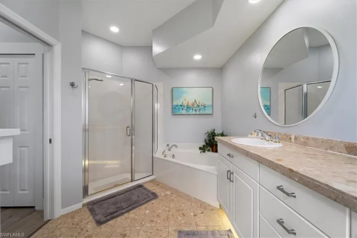 Bathroom featuring vanity, shower with separate bathtub, and tile patterned flooring