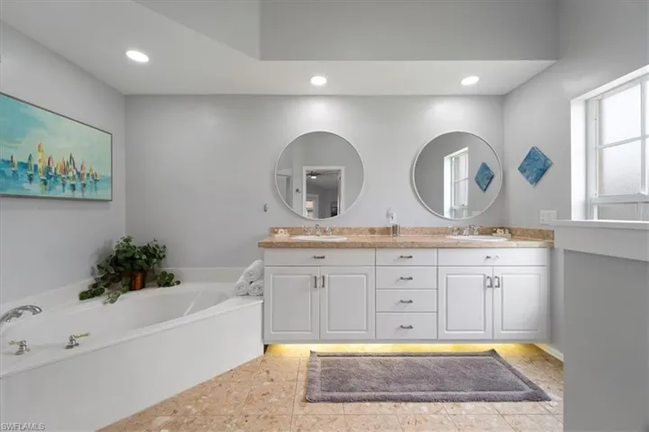 Bathroom featuring double vanity, tile patterned floors, and a bath
