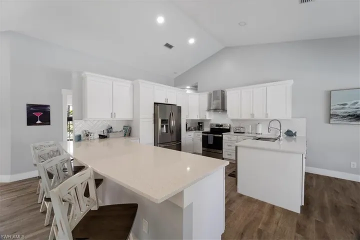 Very Spacious Kitchen featuring a breakfast bar with quartz countertops, high-end white cabinets and beautiful decorative backsplash