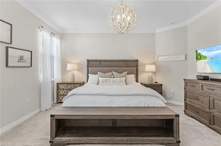 Bedroom featuring baseboards, light colored carpet, a chandelier, and crown molding