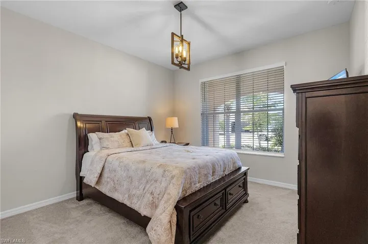 Bedroom featuring a notable chandelier, baseboards, and light carpet