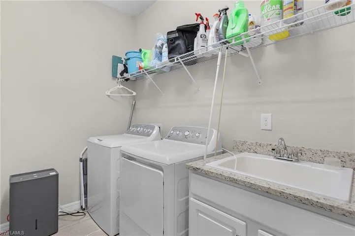 Washroom featuring washing machine and clothes dryer, baseboards, and a sink
