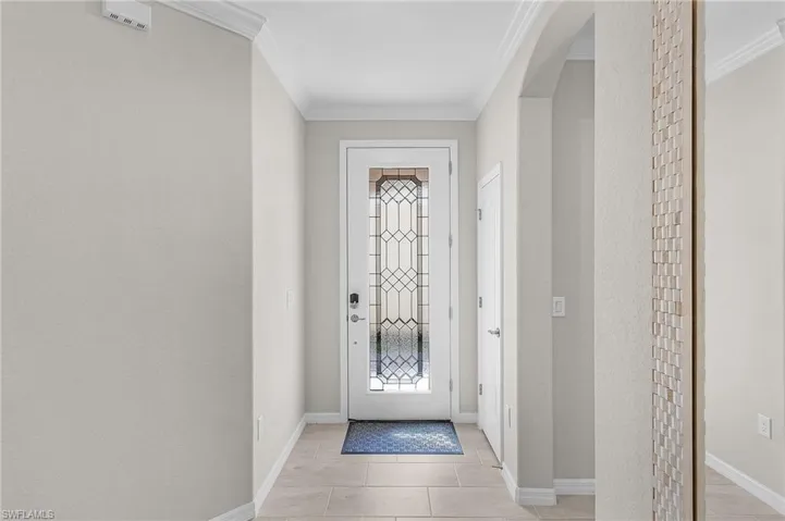 Foyer featuring baseboards, arched walkways, and ornamental molding