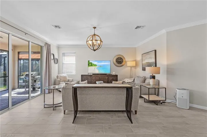 Living room with crown molding, baseboards, visible vents, and a chandelier
