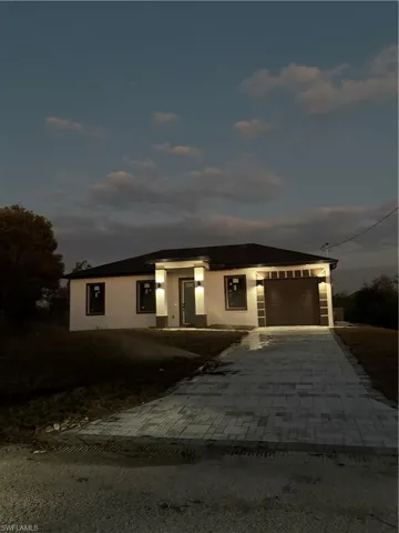Prairie-style home featuring stucco siding, decorative driveway, and an attached garage
