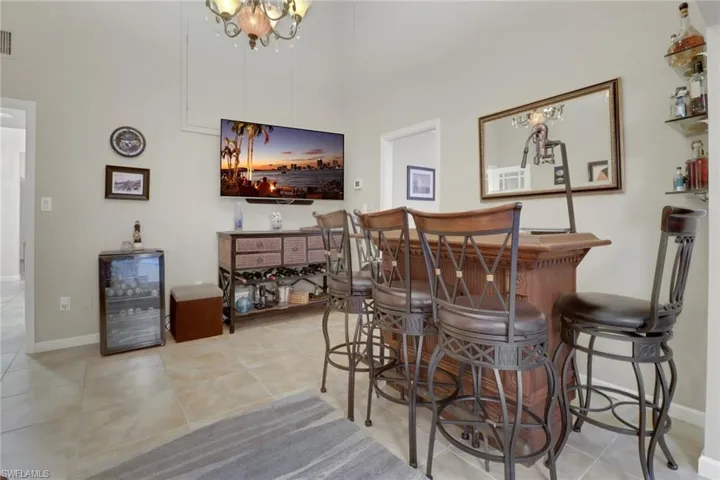 Bar featuring wine cooler, light tile patterned flooring, and an inviting chandelier