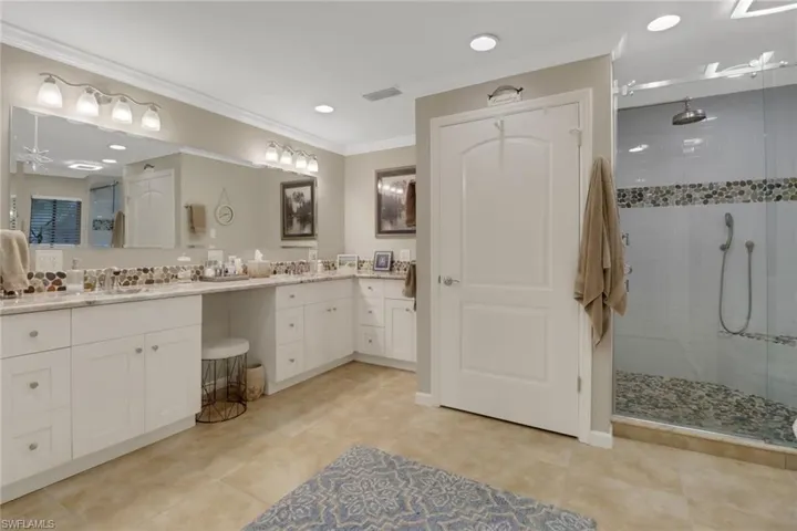 Bathroom with an enclosed shower, vanity, crown molding, and tile patterned flooring