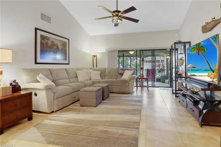 Tiled living room featuring ceiling fan and high vaulted ceiling