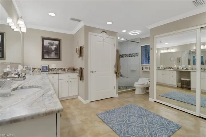 Bathroom with tile patterned floors, vanity, toilet, a shower with shower door, and crown molding