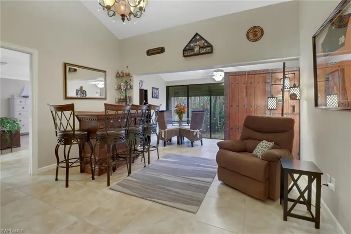 Tiled dining space featuring lofted ceiling, bar area, and an inviting chandelier