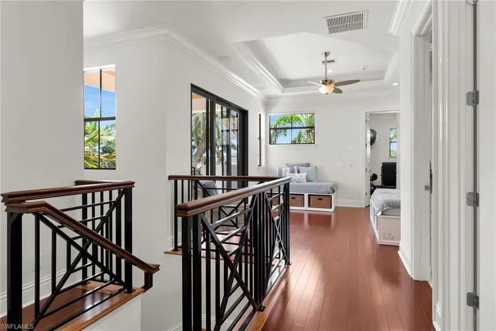 Upper-level landing featuring wood-finish flooring, a tray ceiling, and a ceiling fan
