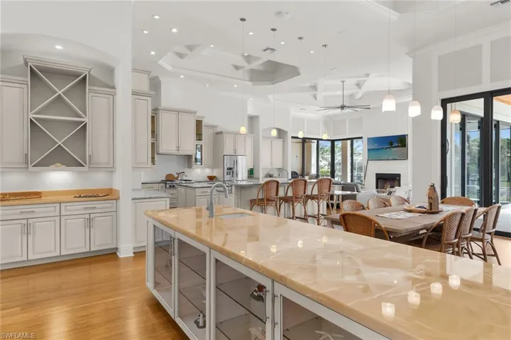 Open-concept living space featuring a large kitchen island with a polished countertop, light-toned cabinetry, and hardwood flooring