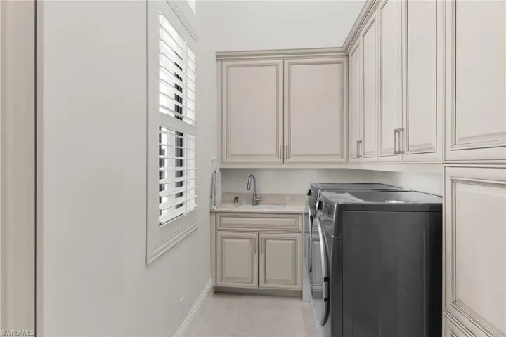 Laundry room featuring built-in cabinetry, light-toned countertops, and a utility sink