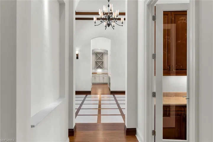 Hallway featuring wood-finish flooring with square tile inlays, arched doorways, and a chandelier