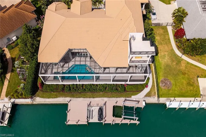 Waterfront property featuring a screened-in pool enclosure, private dock, and boat lift