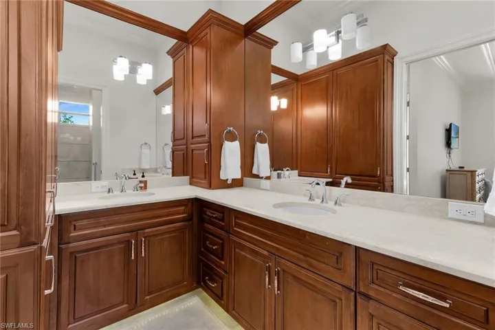 Bathroom vanity featuring dual under-mount sinks, light-toned countertops, and extensive wood cabinetry