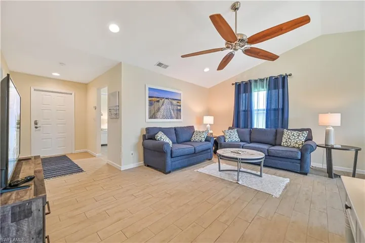 Living area featuring wood tiled floors, ceiling fan, and lofted ceiling