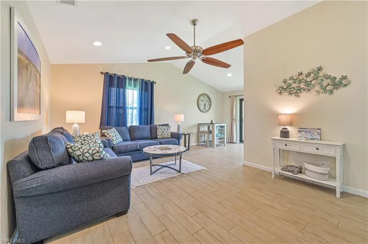 Living room featuring wood finish floors, lofted ceiling, recessed lighting, and ceiling fan