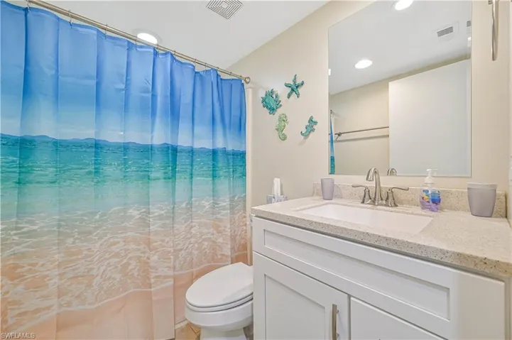 Bathroom with vanity, a shower with shower curtain, and recessed lighting