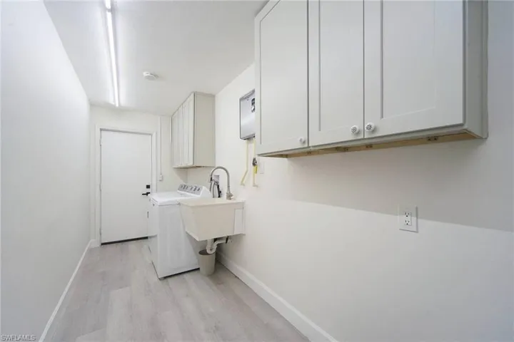 Maytag appliances, utility sink, cabinetry for storage and exit door to side yard