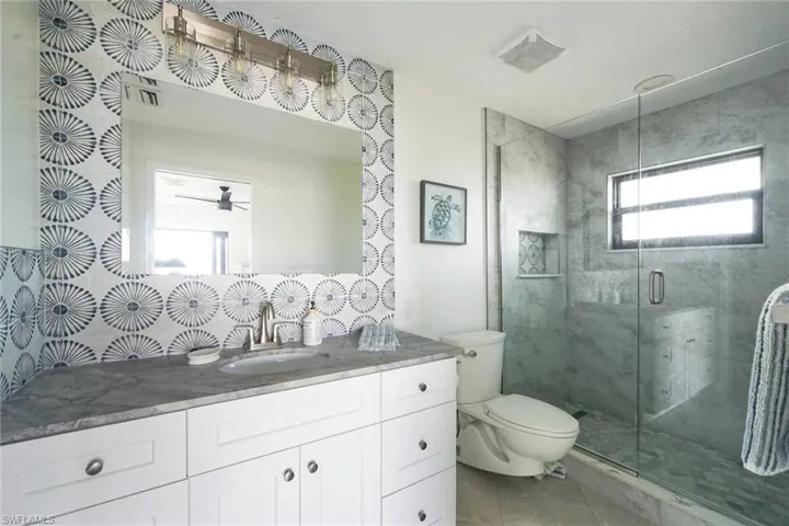 Fully renovated primary bath with frameless shower and beautiful tile. Note that the shower tile extends to the ceiling!