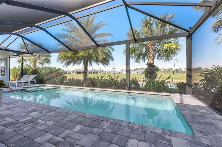View of pool with glass enclosure, a pool with connected hot tub, and a patio area