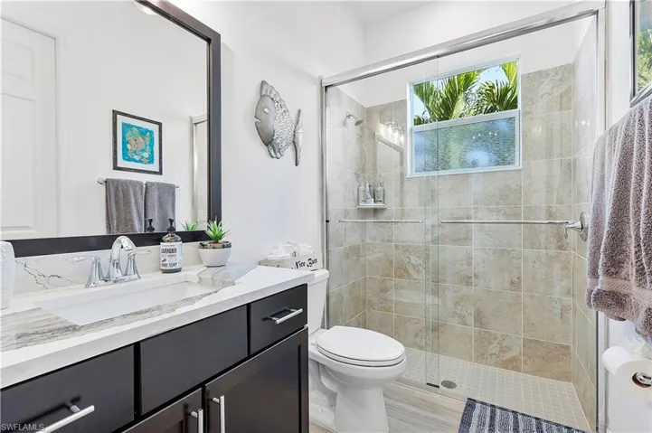 Full bath featuring a shower stall, vanity, and toilet