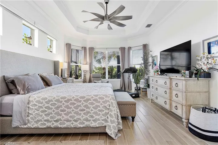 Bedroom featuring ornamental molding, a ceiling fan, a tray ceiling, and wood tiled floor