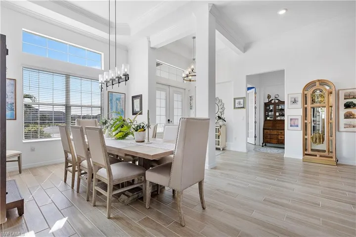 Dining room featuring crown molding, a chandelier, baseboards, a towering ceiling, and wood tiled floor