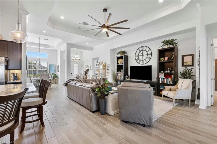 Living room with ceiling fan, crown molding, a raised ceiling, and wood tiled floor