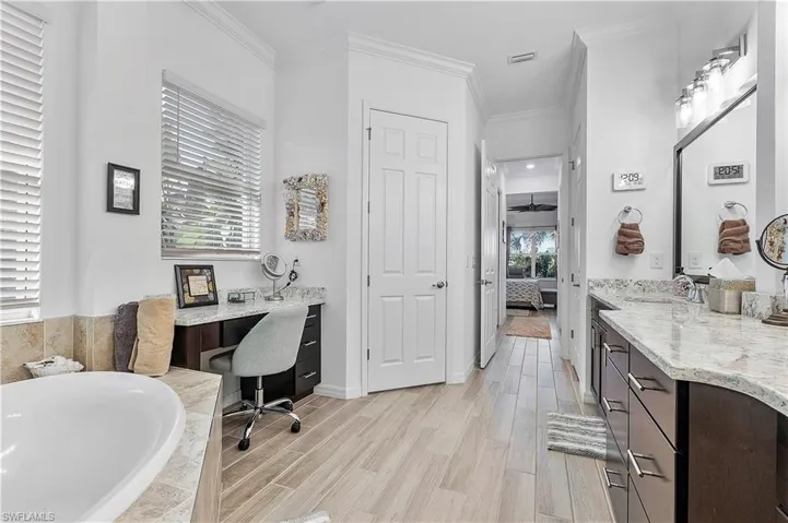Ensuite bathroom with ornamental molding, wood finished floors, tiled tub, and connected bathroom