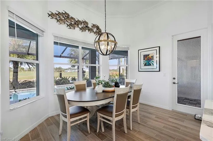 Dining room with light wood finished floors, baseboards, crown molding, and an inviting chandelier