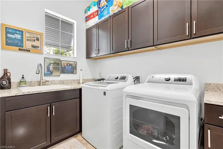 Laundry room featuring washer and clothes dryer, cabinet space, and a sink