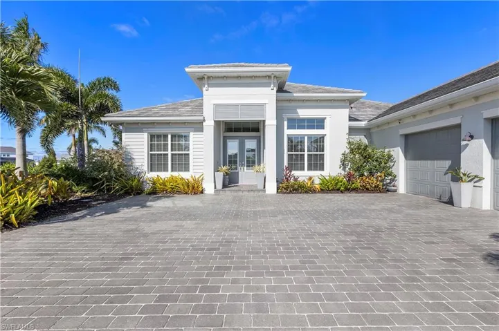View of front of house with french doors, decorative driveway, an attached garage, and stucco siding