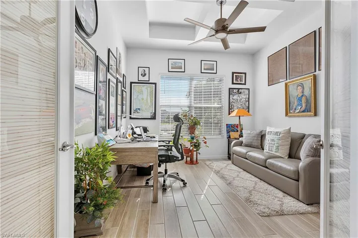 Office space with baseboards, a tray ceiling, ceiling fan, and wood tiled floor
