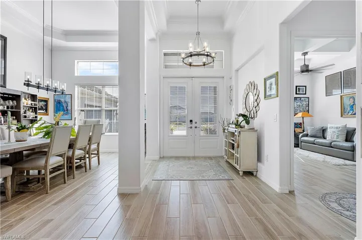 Entryway with baseboards, wood finish floors, ornamental molding, french doors, and a high ceiling