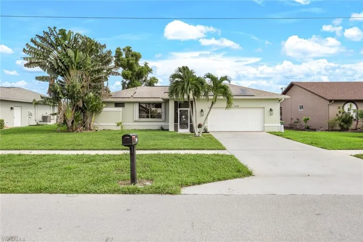Ranch-style home with a front yard, a garage, and solar panels