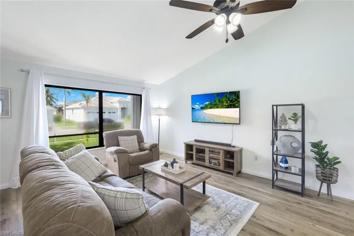 Living room with high vaulted ceiling, ceiling fan, and light hardwood / wood-style floors