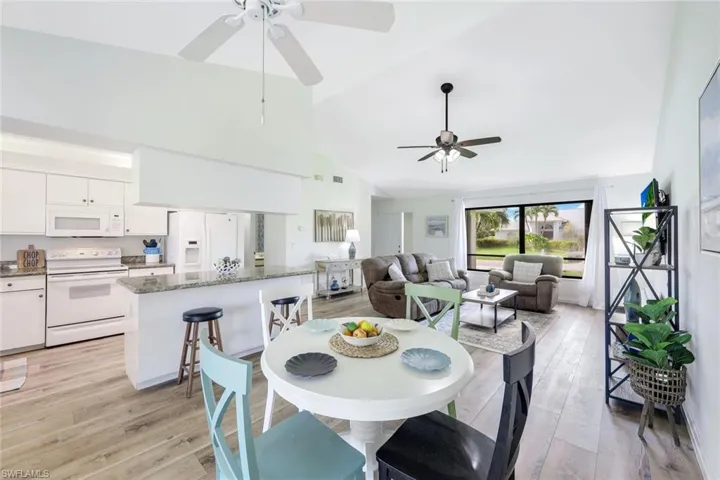 Dining area with light hardwood / wood-style floors, ceiling fan, and high vaulted ceiling